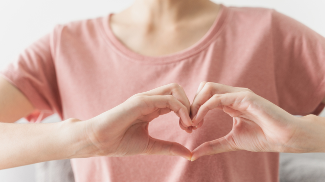 A woman forming a heart with her hands for women's heart health in American Heart Month