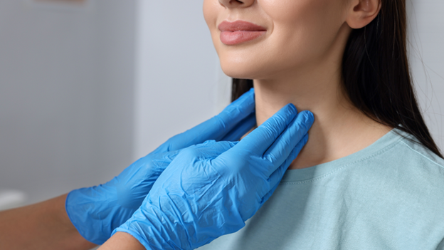 A Village Medical primary care doctor examining a woman for hyperthyroidism vs hypothyroidism