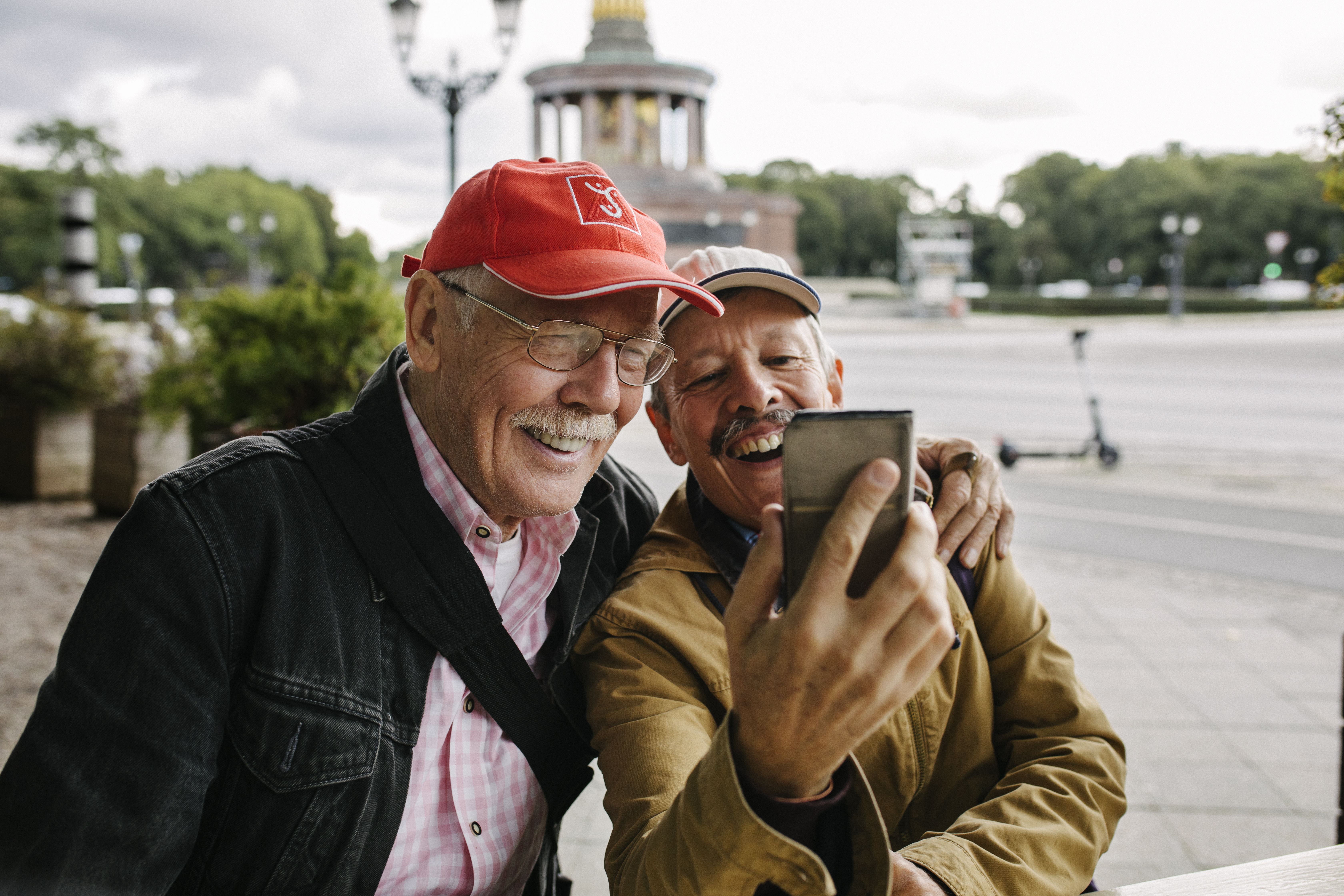 Two smiling men looking at a phone during winter