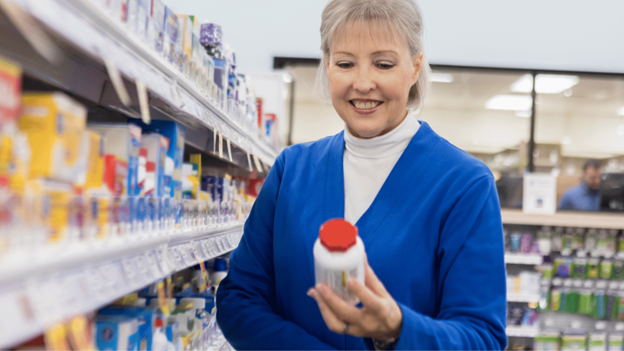Woman comparing OTC pain relievers in a pharmacy